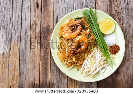 Fried noodle Thai style with prawns. On wood table. Top view.