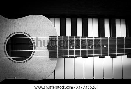 Ukulele on piano key. Top view. Music concept background. Black and white theme. With dark vignette.