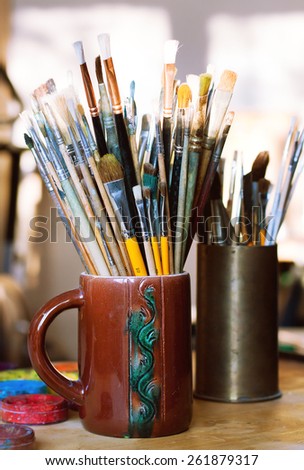 Paint brushes in jar standing on table in workshop
