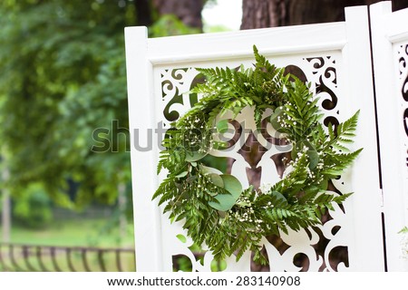 Decorative green wreath on white wooden folding screen as wedding decoration