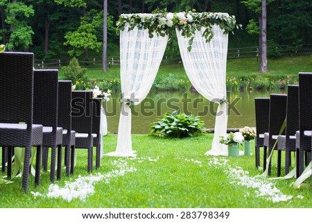 White beautiful arch decorated with flowers on wedding ceremony outdoors