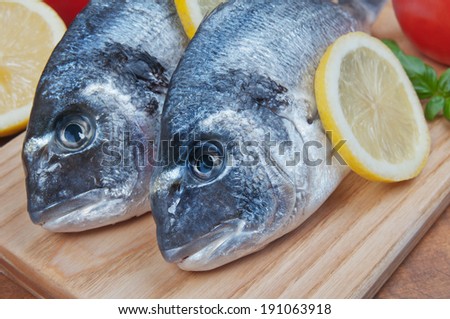 Fresh sea bream fish on a wooden kitchen board
