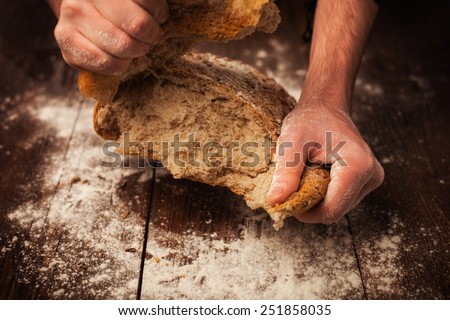 Baker hands with fresh bread on wood table