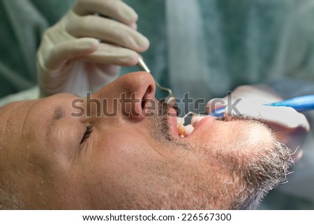 man at the dental clinic while dentist examines tooth cavity and doing general dental cleaning