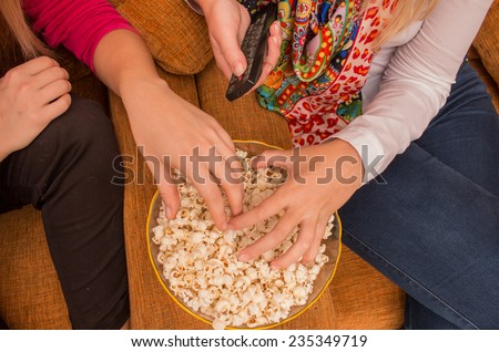 close-up on ladies hands on popcorn while watching tv/home cinema with remote control in hand