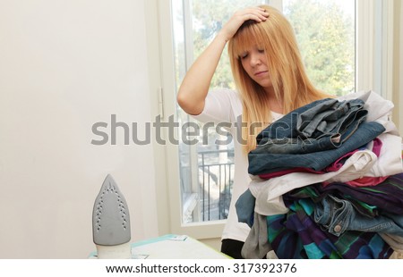 too much domestic work - too many clothes to iron and young exhausted and annoyed housewife at home - focus on pile of clothes to iron