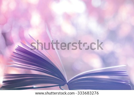 open book lying on table outdoors side view soft focus with blurred background and  purple color tones