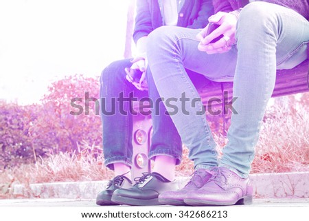 just friends. a shy couple at first meeting, sitting on a park bench with no  physical contact. partial view from the bottom vintage look with attractive pink to purple color tones