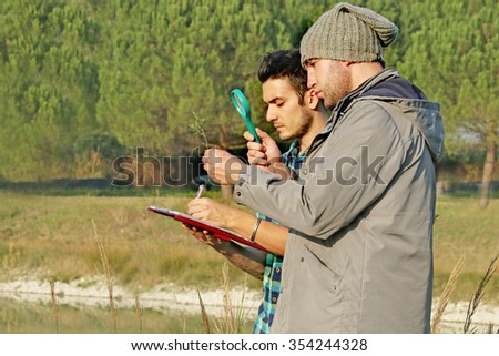 Environmental scientists researching the quality and growth of a natural plant sample and studying bio-diversity - 2 biologists doing botanical tests  -