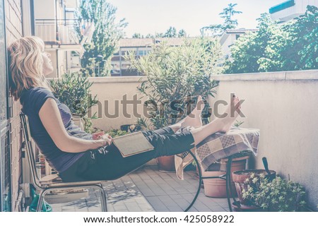 lazy - relaxed blond woman reading, falling asleep in balcony on a warm summer day - custom vintage colors fading and haze effects