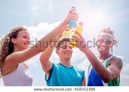 athletes taking a break after training drinking colorful energy drink or sports drink - concept of sports people consuming energetic beverages