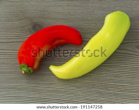 Red and yellow banana peppers on wooden background