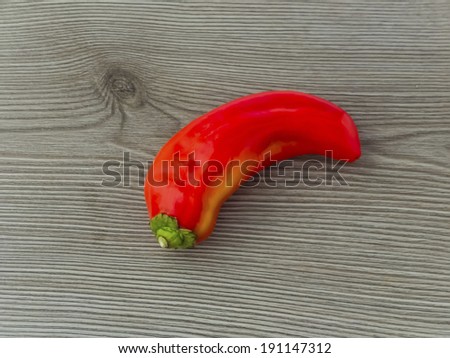 Single red banana pepper on wooden background