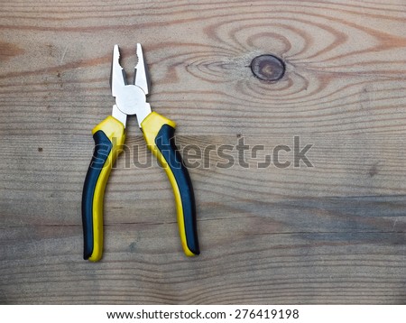 Combination cutting pliers on wooden background. Top view.