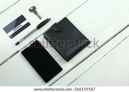 Men\'s wallet, phone, keys and card on wooden table