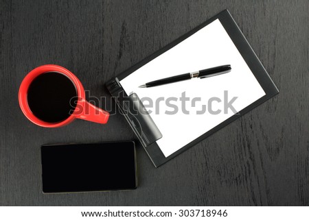 black background, red cup, phone, paper holder, pen