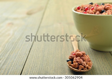light green bowl of muesli with wooden spoon on wooden background