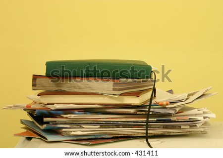 A stack of old magazines and diaries on a white table with a yellow background, with space for designers to add things