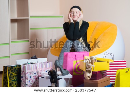 Young pretty woman sitting on a chair in shoes store and dreaming. Woman on the shopping