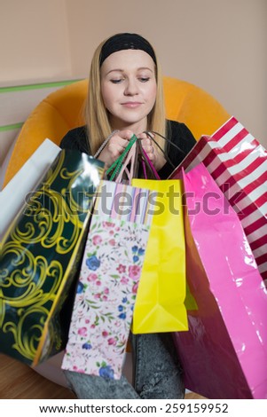 Pretty young woman sitting on the chair and holding a shopping bags. Woman on the shopping