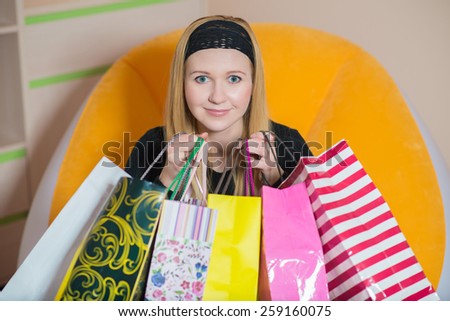 Pretty young woman sitting on the chair and holding a shopping bags. Woman on the shopping