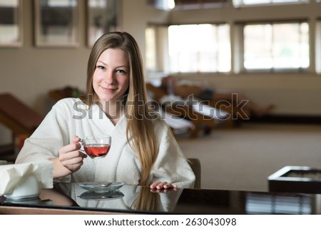 Young pretty woman with cup of green tea in the rest room at the hotel spa