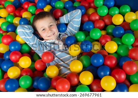 A boy in the playing room with many little colored balls. Close portrait