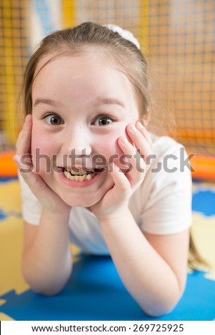 A girl lying and make faces in the children playroom. Close portrait