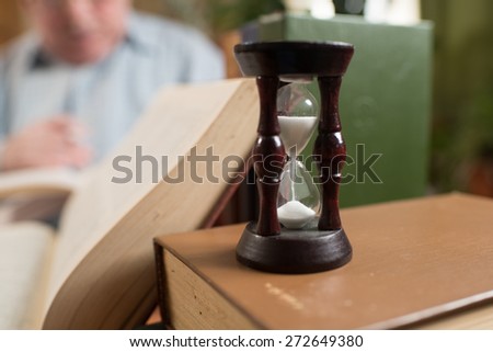 sand clock standing on the desk with books on the background