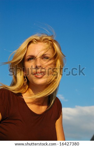 blond woman with fly-away hair against blue sky