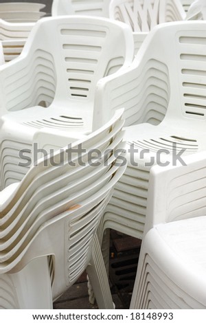 Stack of white plastic chairs on the street