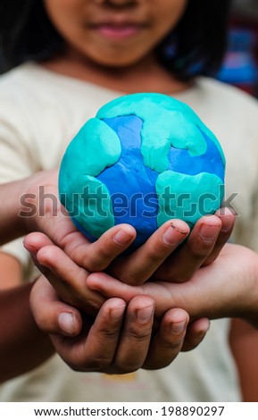 Hands of child holding colorful clay model of Planet Earth