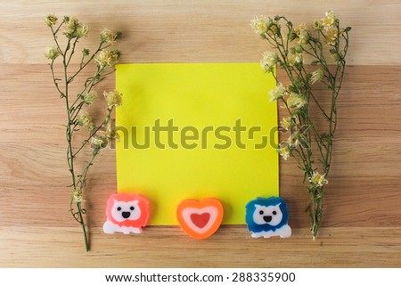 Couple lions heart on yellow paper note and dry flowers on wood background