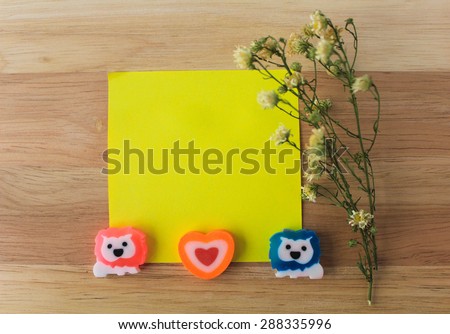 Lovely lions on yellow paper note and dry flowers on wood background