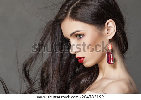 Beautiful woman with bright makeup and long brown hair wearing fine jewelry