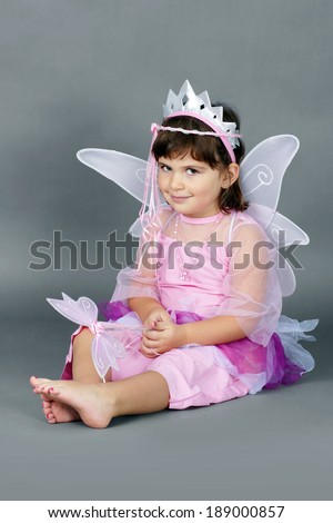 Cute little girl dressed up as pink fairy princess resting