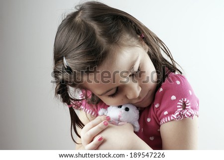 Little girl hugging plush or stuffed toy, desaturated