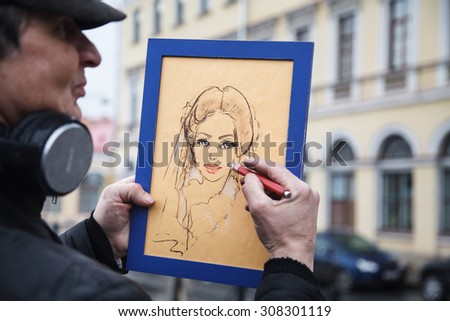 St. Petersburg, Malaya Konyushennaya, February 14, 2015. Artist paints a portrait. Street artist. Art. Drawing with pastel and pencil on cardboard.