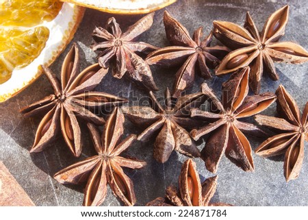 A lot of star anises, near dried fruit, on a stone plate