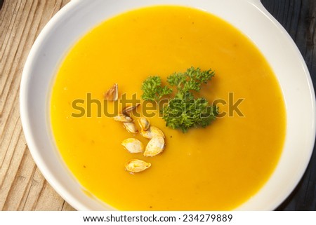 Orange pumpkin soup, roasted pumpkin seeds and green parsley
