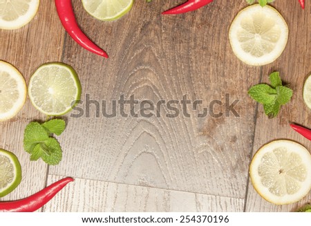 Chili, lime, mint and lemon background, on wooden background