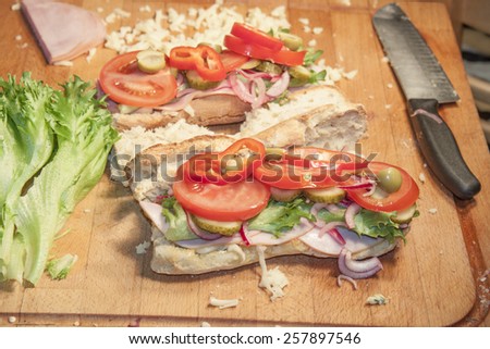 French bread sandwich, filled with ham, salad, red onion and tomato