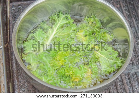 Deep frying green kale, in a frying pot