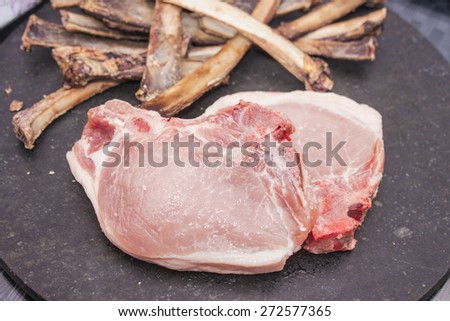 Raw Pork cutlet, in front of a pile of bones
