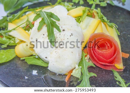 Mozzarella salad, made of rucola, yellow zucchini, salad and a tomato rose flower