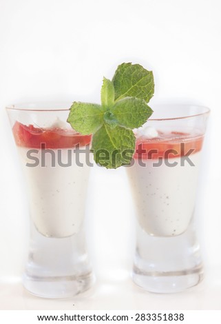 Two glasses of vanilla pannacotta topped with rhubarb and mint