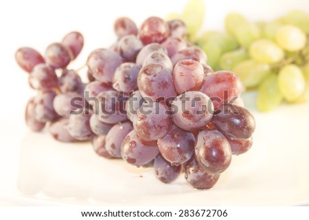 Purple grapes, in front of green grapes, isolated on white background