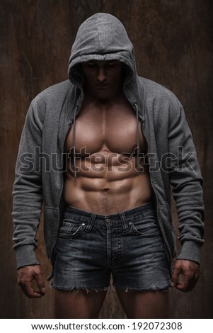 Young muscular man with open jacket revealing muscular chest and abs.