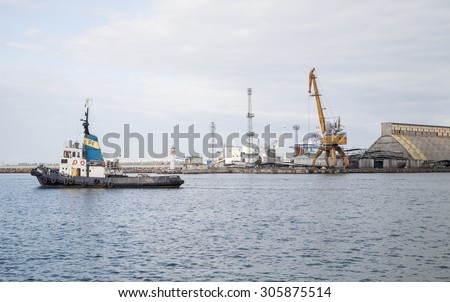 Burgas - June 9: Small boat - a guide in port sail amid cranes, administrative and industrial buildings of June 9, 2015, Burgas, Bulgaria