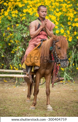 CHIANGRAI, THAILAND NOVEMBER 16,2014  priest ride a horse beg for food Festival Mexican sunflower in the Doi Hua Mae Kham